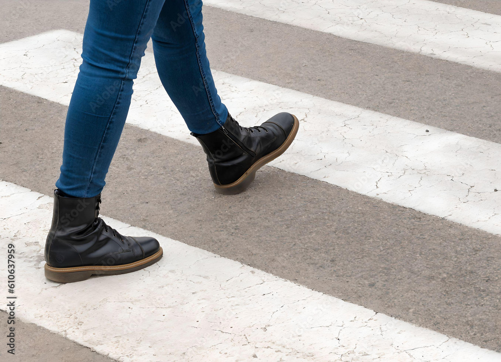 Pedestrians crossing. Woman legs in boots crossing the zebra crossing Pedestrians crossing. Woman legs in boots crossing the zebra crossing