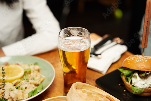 Close-up of young multiracial couple in casual clothing having dinner and drinks at restaurant