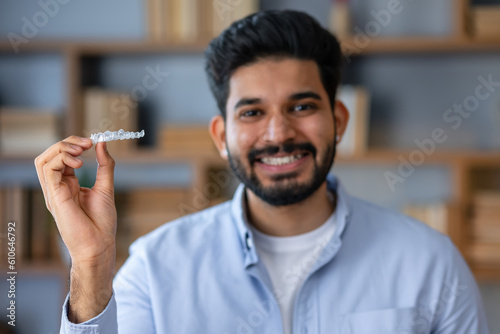 Young arab man with beard holding invisible aligner orthodontic and braces looking positive and happy standing and smiling with a smile showing teeth