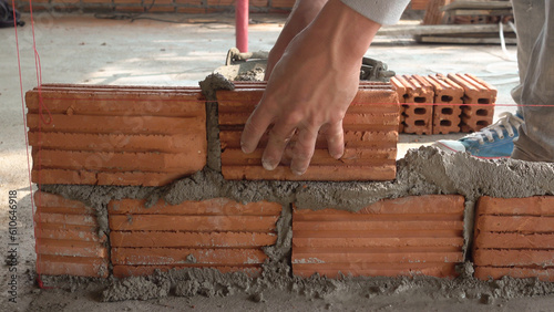 Bricklayer worker installing brick masonry on exterior wall