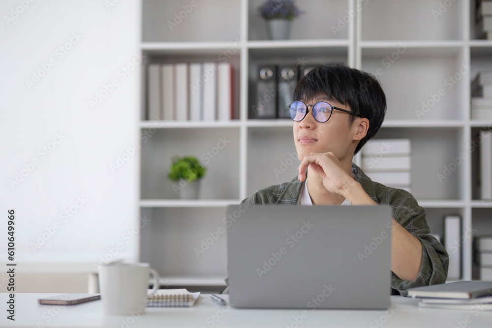 Young Asian man working at home using a laptop computer on a table. Young Asian man working at home using a laptop computer on a table.