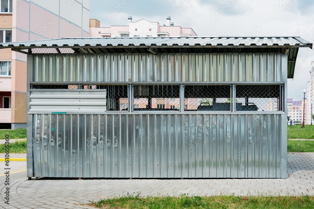 Trash containers block for flat garbage collect behind metal fence on courtyard of residential house or condominium Trash containers block for flat garbage collect behind metal fence on courtyard of residential house or condominium