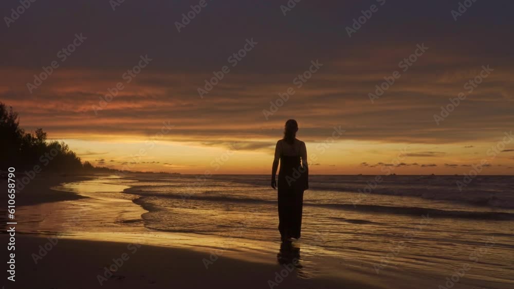 Young happy romantic girl is walking at sunset beach. Full length. Back view. Young happy romantic girl is walking at sunset beach. Full length. Back view.