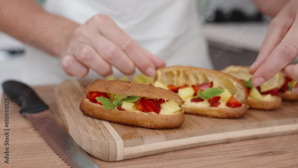 The pastry chef has filled the pastries with the berry filling and covers them with the second half one by one. slow motion. The pastry chef has filled the pastries with the berry filling and covers them with the second half one by one. slow motion.
