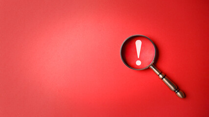 Magnifier magnifying exclamation mark on red background. Alert and precaution concept. Caution and risk management security signal announcement hazard and dangerous notice symbol