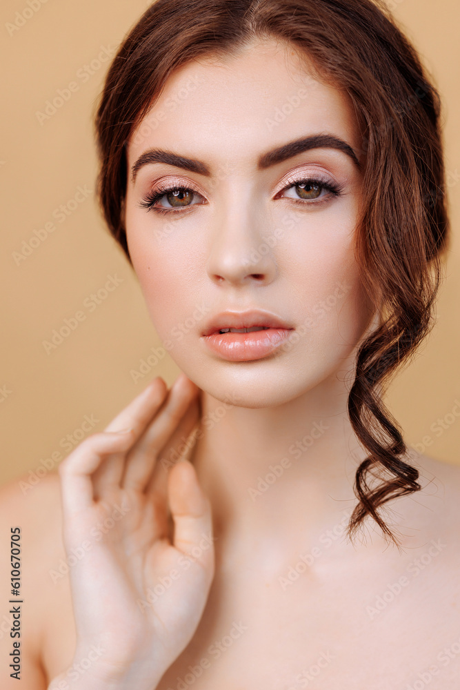 Portrait of a beautiful woman looking at the camera isolated on a beige background with copy space. Concept of cosmetology procedures or natural natural beauty or cosmetic product advertising.