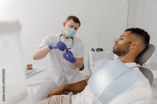 In the modern dental clinic the dentist doctor man showing to the patient how the implants working and explains the process of work