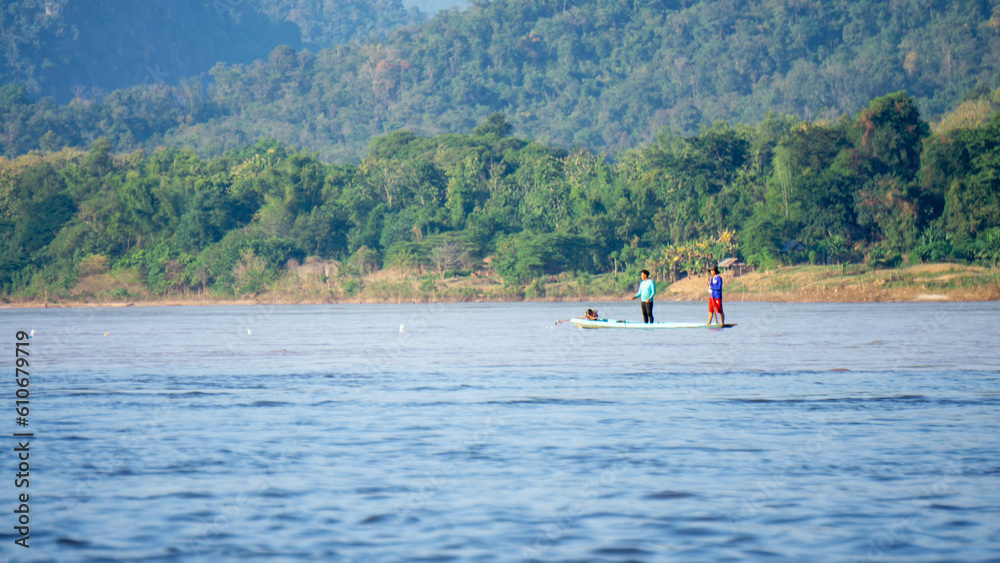 Naklejka premium 3 Asians on a pirogue on the mekong river in Luang Prabang, Laos