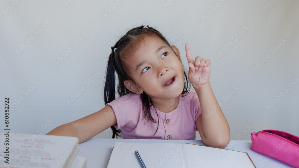 imaginative asian schoolgirl thinking while doing homework on the table. imaginative asian schoolgirl thinking while doing homework on the table.