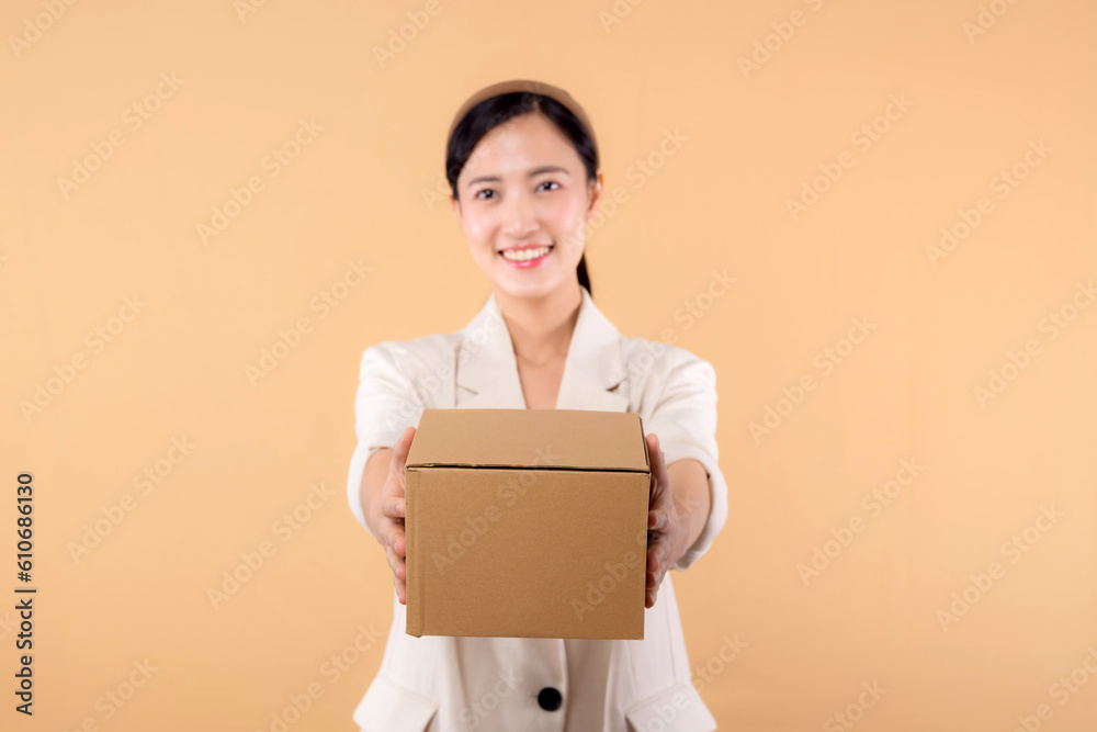 portrait of happy successful confident young asian business woman wearing white jacket holding parcel box isolated on beige studio background, Delivery courier and shipping service concept. portrait of happy successful confident young asian business woman wearing white jacket holding parcel box isolated on beige studio background, Delivery courier and shipping service concept.