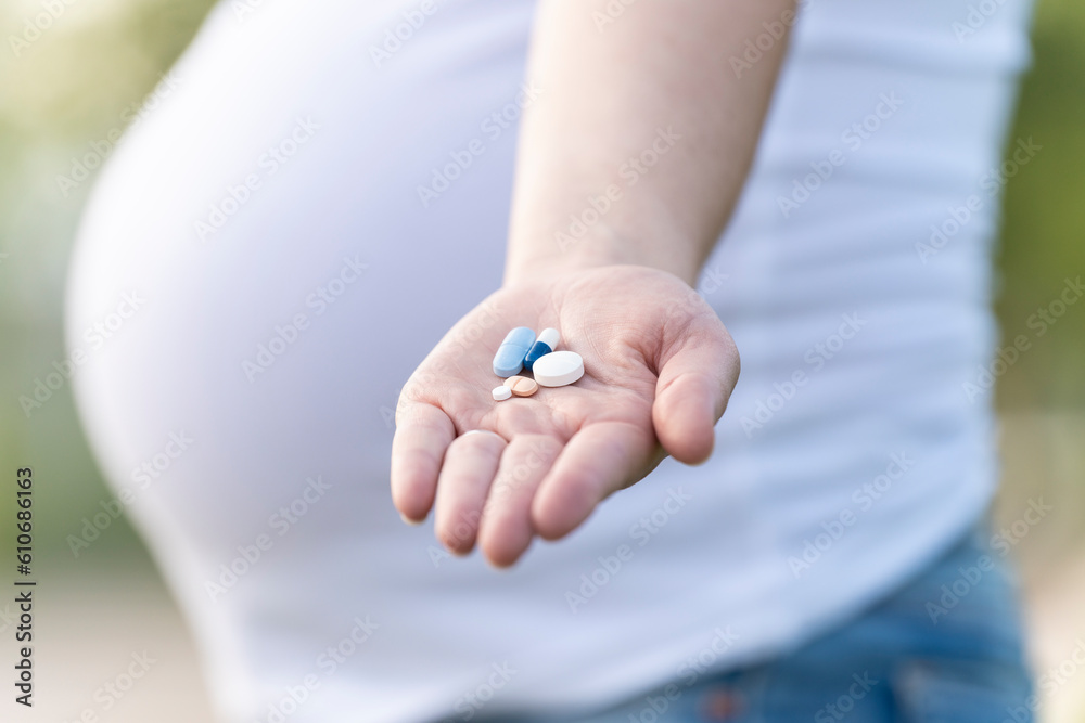 Pregnant woman showing some pills in her hand Pregnant woman showing some pills in her hand