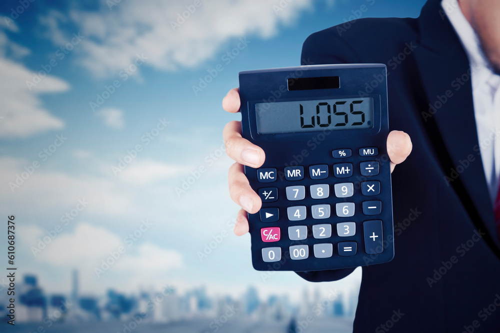 Businessman holding a calculator with loss text on display Businessman holding a calculator with loss text on display
