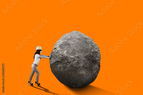 Female engineer with safety helmet pushing big rock