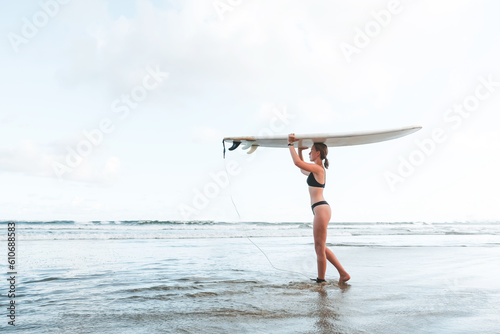 Surfing, Girl surfer with a longboard on the beach of Weligama, Indian Ocean Active water sports, travel, surf school, surf camps. Active lifestyle