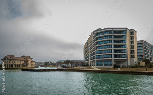 Waterfront condominium building and private home, on a mostly cloudy day.