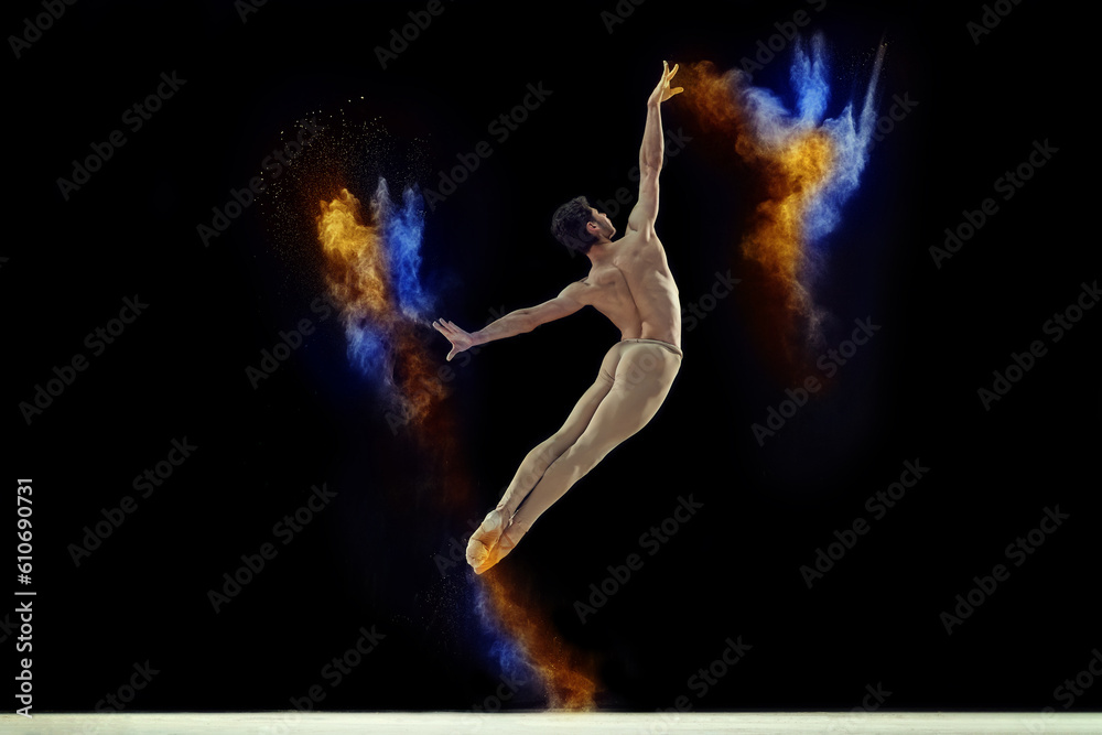 Talented, artistic young man, ballet dancer in beige bodysuit performing with colorful explosion of powder over black studio background. Concept of art, festival, beauty of dance, inspiration, youth