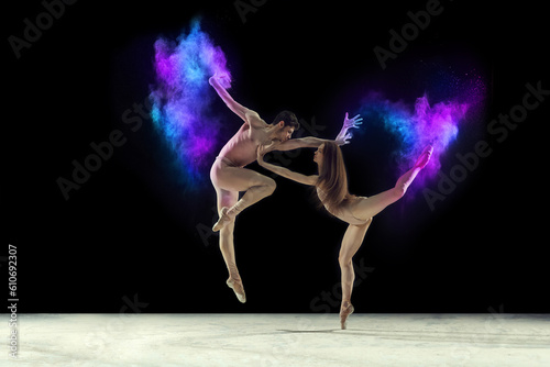 Fototapeta Naklejka Na Ścianę i Meble -  Passion. Young graceful ballet dancers, man and woman ion beige bodysuits dancing with powder explosion against black studio background. Concept of art, festival, beauty of dance, inspiration, youth