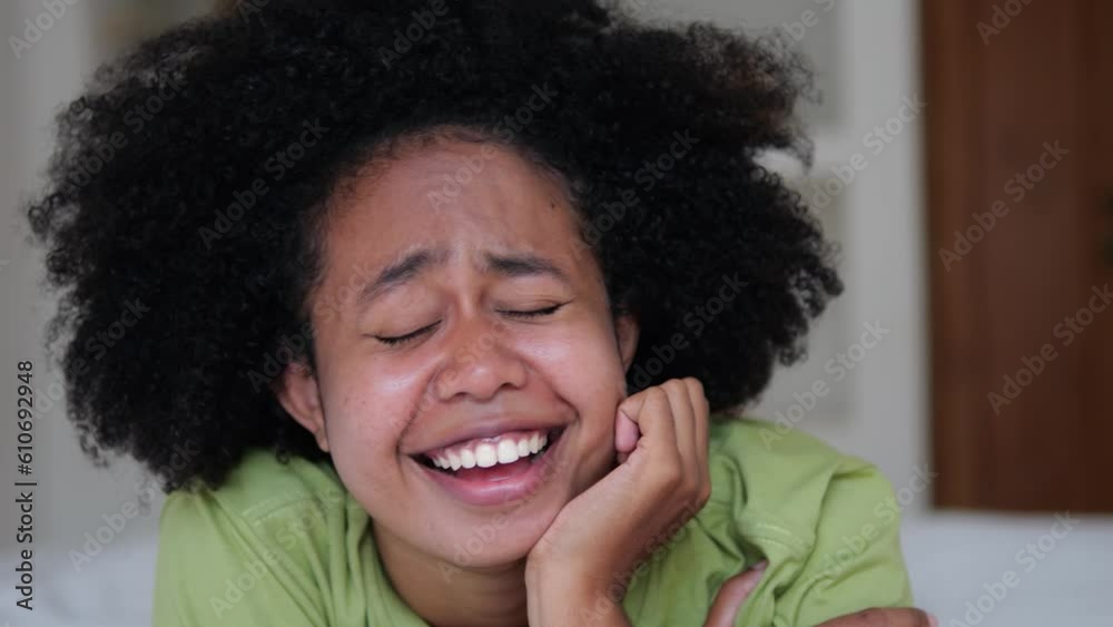 Close up happy cheerful black woman laughs and smiles with her head propped on palm. Portrait of a black emotional feminine woman with black curls. A cheerful conversation full of laughter and joy Close up happy cheerful black woman laughs and smiles with her head propped on palm. Portrait of a black emotional feminine woman with black curls. A cheerful conversation full of laughter and joy
