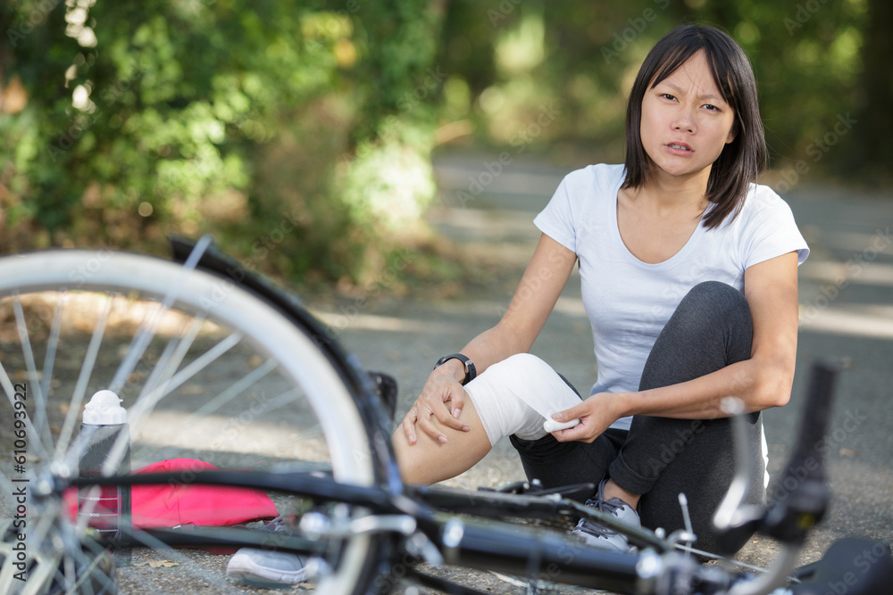 Obraz premium sad woman fell off mountain bike bandaging her knee