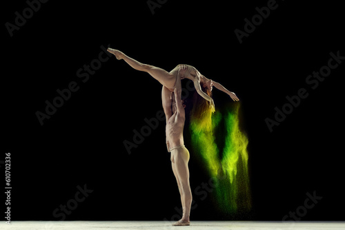 Fototapeta Naklejka Na Ścianę i Meble -  Attractive, talented, young man and woman, ballet dancers making colorful performance with powder explosion over black studio background. Concept of art, festival, beauty of dance, inspiration, youth