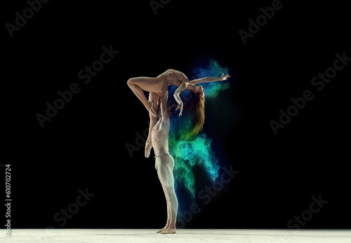 Attractive, talented, young man and woman, ballet dancers making colorful performance with powder explosion over black studio background. Concept of art, festival, beauty of dance, inspiration, youth © master1305