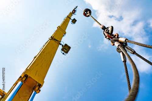 The hydraulic cylinders of an offshore oil rig crane are using four strong slings to lift large loads with four corner sling handles.