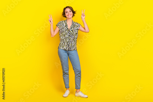 Full size photo of funny nice lady excited show v sign symbols hands wear print blouse jeans shoes isolated yellow color background