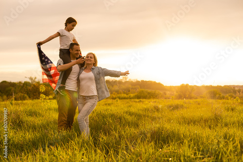 Happy family in wheat field with USA american flag on back.