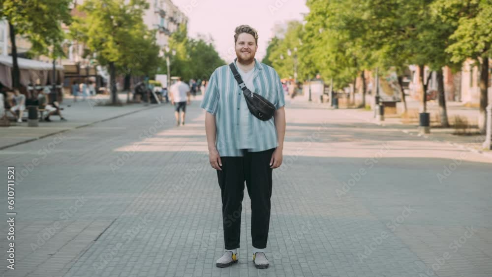 Time lapse portrait of man in stylish outfit standing in city center looking at camera with people walking around. Time lapse portrait of man in stylish outfit standing in city center looking at camera with people walking around.