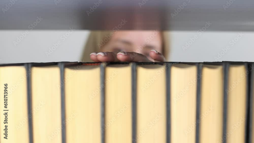 Women's hands choose a book on a shelf. Women's hands choose a book on a shelf.