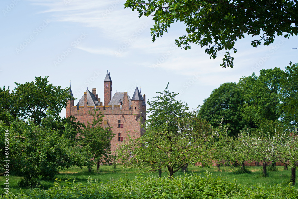Medieval castle Doornenburg between trees in Doornenburg in the Netherlands with a blue sky with some clouds