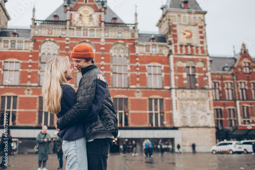Photography Smiling young couple on in front of the red brick train station in Amsterdam in