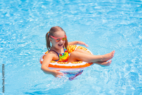 Child in swimming pool on toy ring. Kids swim.