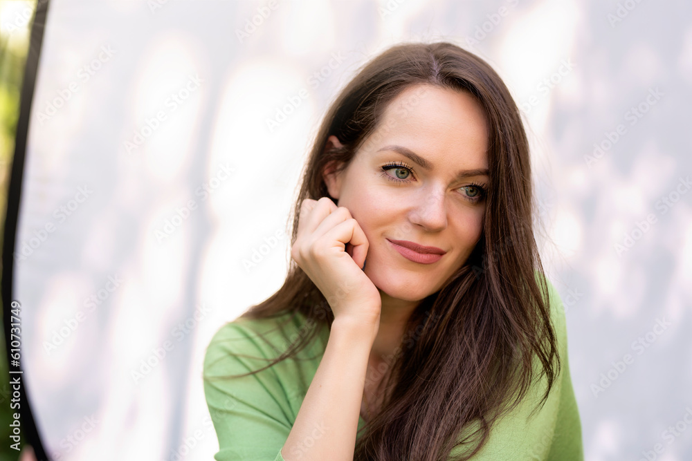 Portrait of young woman with beautiful green eyes and brunette hair sitting at sunglight Portrait of young woman with beautiful green eyes and brunette hair sitting at sunglight