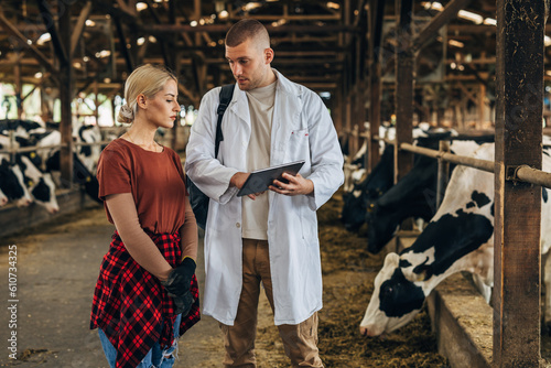 A vet speaks to a female farmer in a barn about th cows.