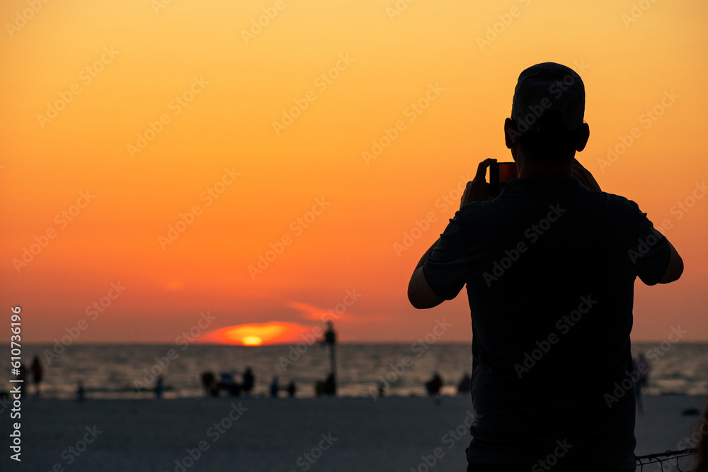 silhouette of a person taking a picture of the sunset 