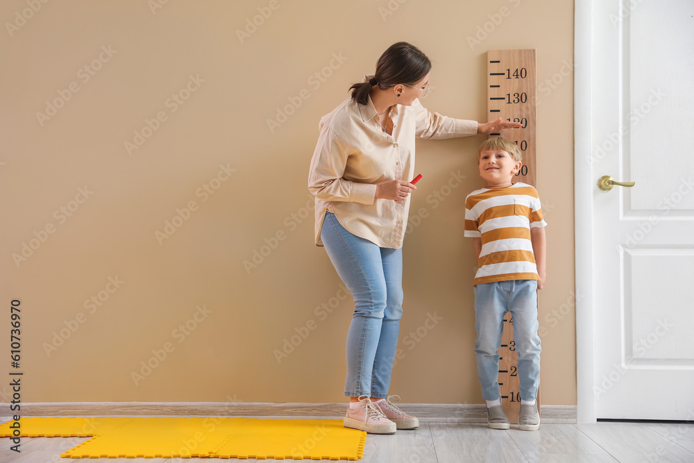 Little boy with nanny measuring height at home - obrazy, fototapety, plakaty 
