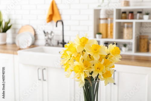 Vase with blooming narcissus flowers in interior of kitchen, closeup