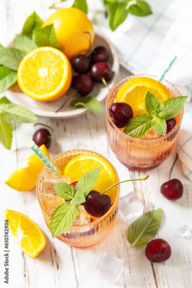 Iced refreshment drink orange cherry cola lemonade or mojito cocktail in glass on a wooden table. Fresh summer drink. Iced refreshment drink orange cherry cola lemonade or mojito cocktail in glass on a wooden table. Fresh summer drink.
