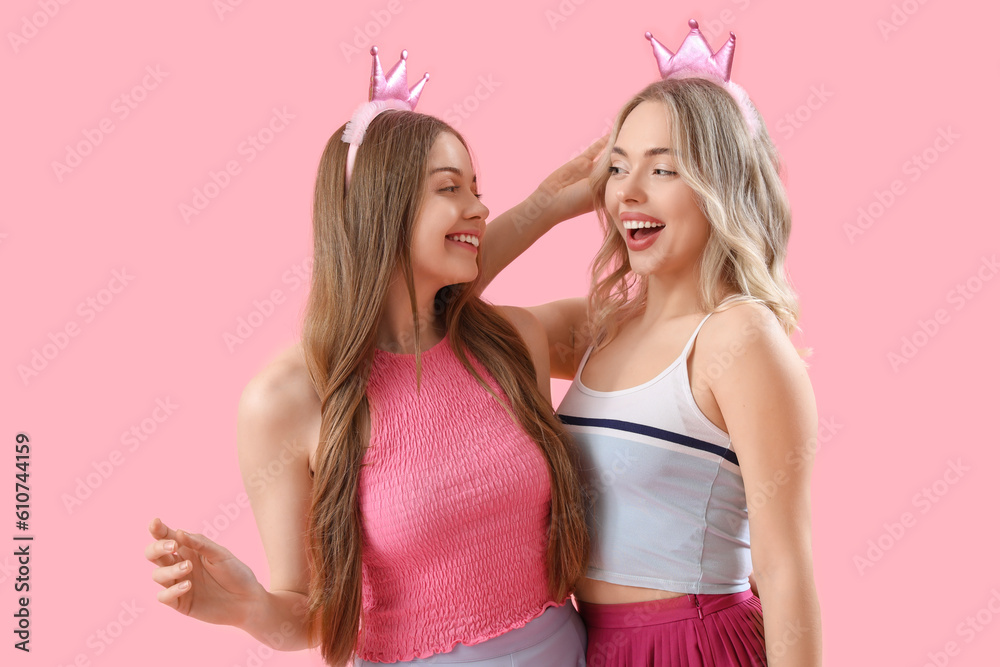 Young sisters in crowns on pink background Young sisters in crowns on pink background