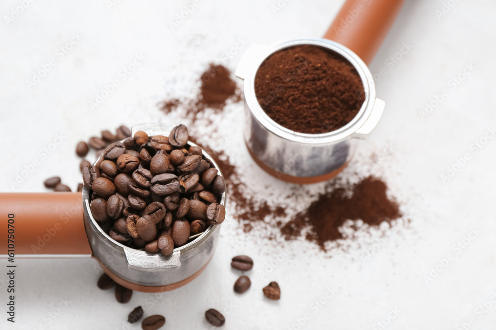 Obraz premium Portafilters with coffee beans and powder on light background