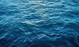  the water is very blue and it looks like it has a lot of ripples on the surface of the water and the sun is shining on the horizon.  generative ai
