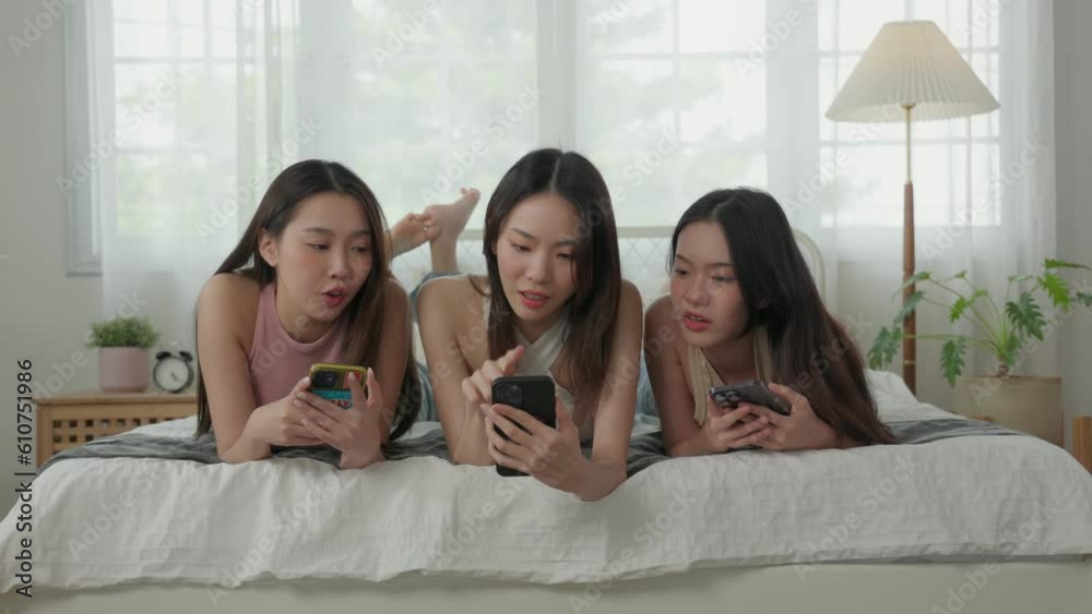 Group of Young Asian woman lying down on bed enjoy use a smartphone Group of Young Asian woman lying down on bed enjoy use a smartphone