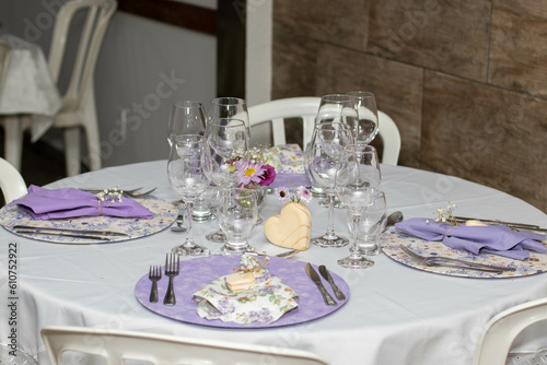 Mesa elegante com pratos decorados, rosas, flores, copos e taças de cristal
