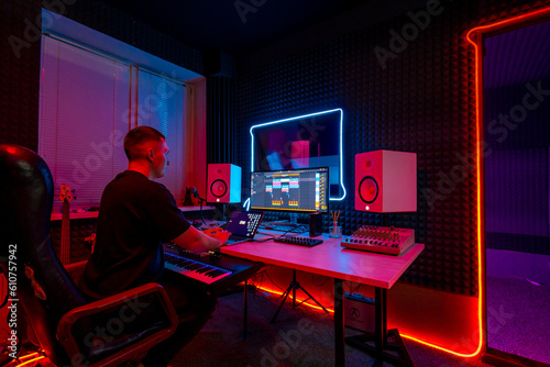 professional sound recording studio sound engineer or music producer sitting at the remote control mixing tracks on the screen neon light