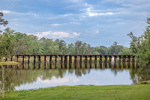 A railroad track bridge over a public lake called Cherokee Lake  in Thomasville Georgia on a Sunny day with a tranquil and peaceful scene