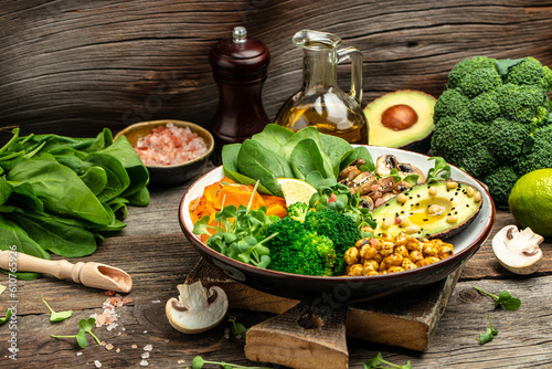 vegetable vegetarian buddha bowl avocado, mushrooms, broccoli, spinach, chickpeas, pumpkin on a wooden background. top view