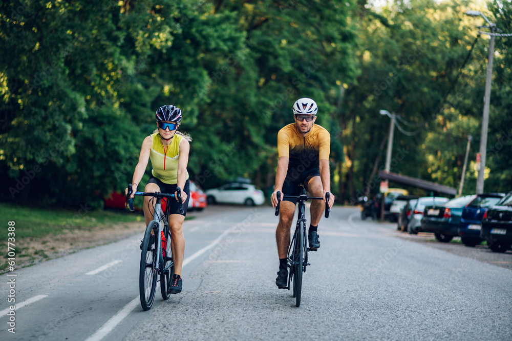 Couple riding bicycles outside of the city and wearing helmets and sunglasses Couple riding bicycles outside of the city and wearing helmets and sunglasses