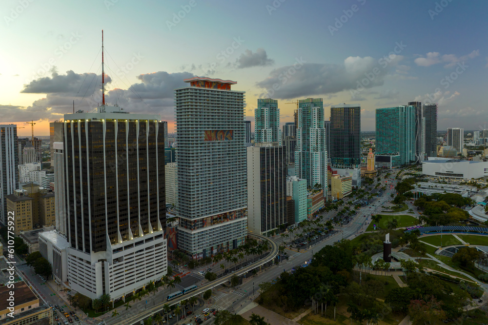 Obraz premium Aerial view of downtown district of of Miami Brickell in Florida, USA at sunset. High skyscraper buildings and street with cars and Metrorail traffic in modern american midtown