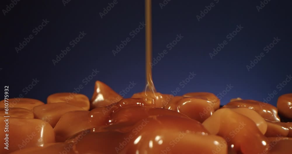 Pouring sweet caramel sauce on caramel background, motion, close up